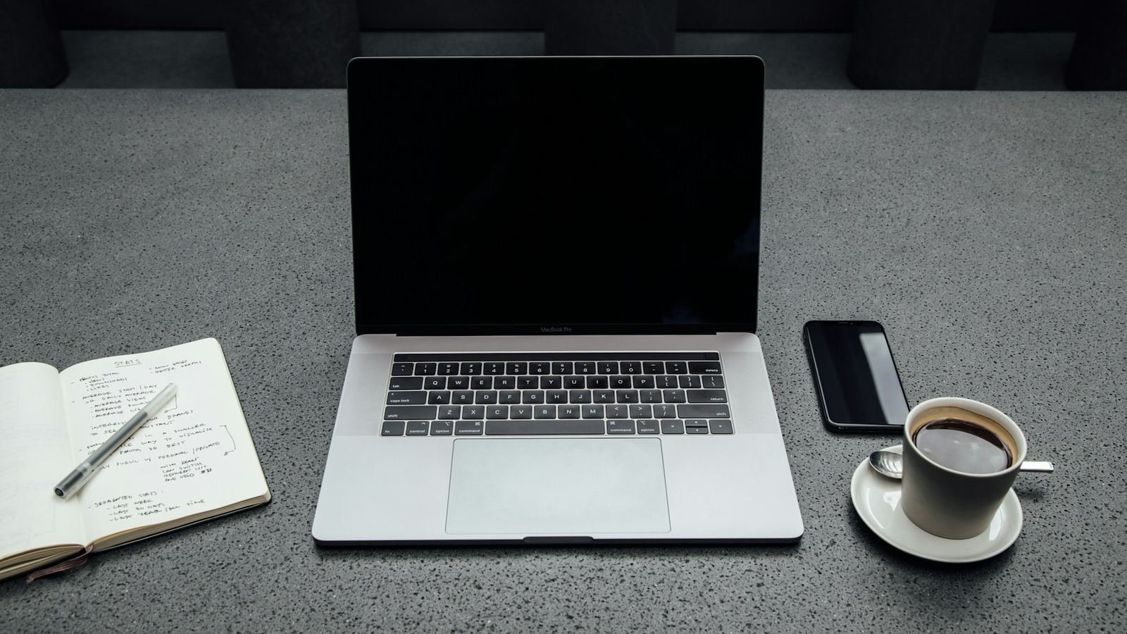 Laptop, taleefan, buug yar iyo koob shaah oo saaran miis