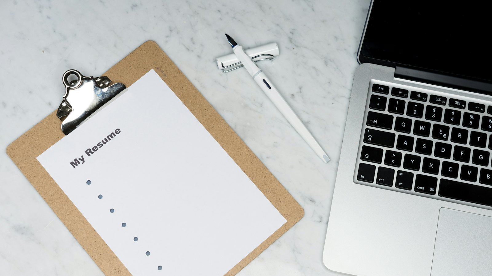 Warqad CV ah oo ku dheggan clipboard, laptop agtiisa